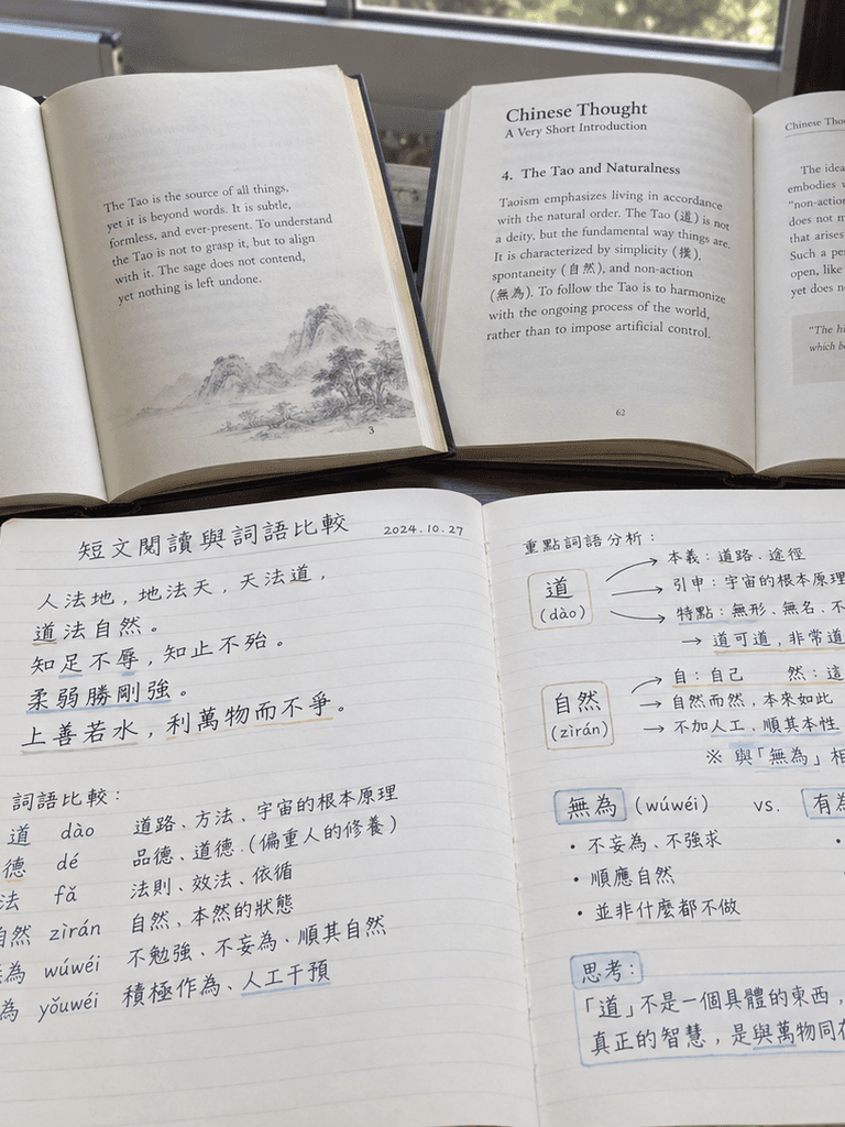 Two open books beside a notebook comparing words in a short Chinese passage